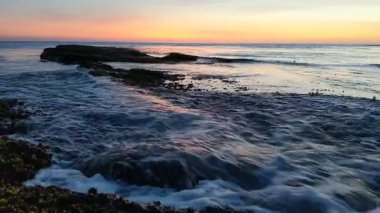 Swamis Resif Parkı Encinitas California 'da günbatımında eski resifler, gel-git havuzları, okyanus dalgaları, palmiye ağaçları, deniz kuşları ve sıcak renkli gökyüzüyle birlikte Güney Kaliforniya kıyısı sahneleri..