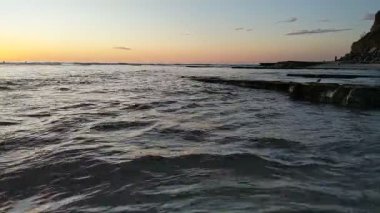 Güney Kaliforniya plaj sahnesi 4K video gelgit havuzları, soyut kaya oluşumları, okyanus dalgaları, sörf tahtaları ile sörfçüler Swamis Resif Parkı Encinitas California 'da sıcak güneşli gökyüzü.