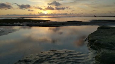 Güney Kaliforniya plaj sahneleri gelgit havuzları, soyut kaya oluşumları, okyanus dalgaları sörf tahtaları, gün batımı siluetleri ve Swamis Resif Parkı Encinitas California 'da sıcak şeftali rengi gökyüzü..