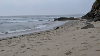 Swamis Sahili 'nin soğuk erimiş kayaları. 50 yıl önce kıyı şeridi boyunca uzanan okyanus dalgası erozyon kontrol taşları şimdi Swamis Resif Sörf Parkı Encinitas California 'daki antik nehir kayalarıyla çevrili soyut heykellere benziyor..