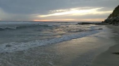 Güney Kaliforniya Pasifik sahili antik resifler, gelgit havuzları, okyanus dalgaları, palmiye ağaçları, sörf tahtaları ve deniz kuşlarının yanı sıra günbatımı gökyüzü manzarası ve Swamis Resif Parkı Encinitas 'taki serin kaya soyutlamaları..