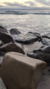 Swamis Sahili 'nin soğuk erimiş kayaları. 50 yıl önce kıyı şeridi boyunca uzanan okyanus dalgası erozyon kontrol taşları şimdi Swamis Resif Sörf Parkı Encinitas California 'daki antik nehir kayalarıyla çevrili soyut heykellere benziyor..