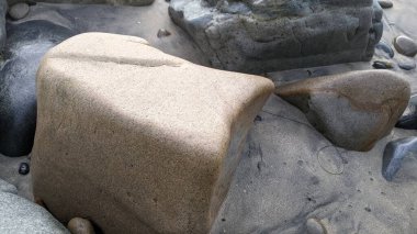 Swamis Sahili 'nin soğuk erimiş kayaları. 50 yıl önce kıyı şeridi boyunca uzanan okyanus dalgası erozyon kontrol taşları şimdi Swamis Resif Sörf Parkı Encinitas California 'daki antik nehir kayalarıyla çevrili soyut heykellere benziyor..