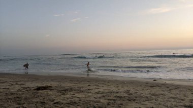 Swamis Sahili 'nde Sunset Sky. Güney Kaliforniya 'da uzak kumsallar, günbatımları, sörfçüler, gelgit havuzları, dalgalar yontulmuş kayalar, palmiye ağaçları ve Encinitas kıyı bölgesindeki Swamis Resif Sörf Parkı' nda şiddetli kış fırtınaları..