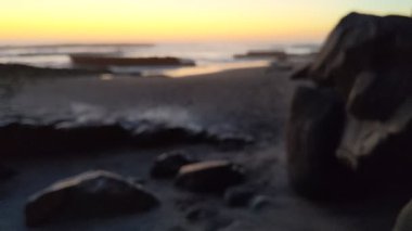 Swamis Sahili üzerinde günbatımı gökyüzü. Güney Kaliforniya 'da uzak kumsallar, günbatımları, sörfçüler, gelgit havuzları, dalgalar yontulmuş kayalar, palmiye ağaçları ve San Diego' nun kuzeyindeki Encinitas sahillerindeki Swamis Resif Sörf Parkı 'nda şiddetli kış fırtınaları..