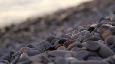Sahilde küçük kayaları yıkamak, gün batımı ışığı, yaklaş, rafa odaklan, 4K.