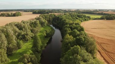Nehrin havadan görünüşü, sonbaharda gün doğumu, nehir boyunca uzanan ağaçlar, arka planda tarım arazileri.