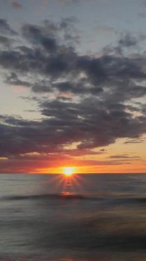 Okyanusun üzerinde dramatik bulutlarla gün batımı. Dikey video