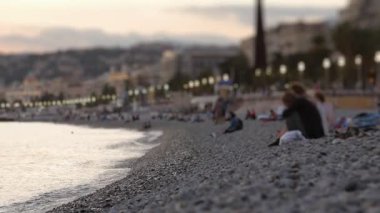 Gün batımından sonra Fransa 'nın güzel kumsalında dinlenen tanınmamış insanlar, sığ bir alan derinliği..