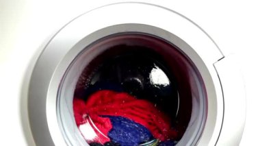 Çamaşır makinesi renkli giysileri ve çarşafları yıkıyor çamaşır günü silindiri arka planda dönüyor