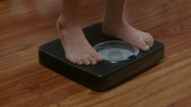 幸せな若い女性が家で体重計を踏んで 減量の概念は重量損失の成功の食事療法を点検する — ストック動画