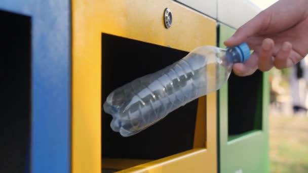 リサイクルゴミの分別のためにカラフルなビンにペットボトルを投げる公害環境 — ストック動画