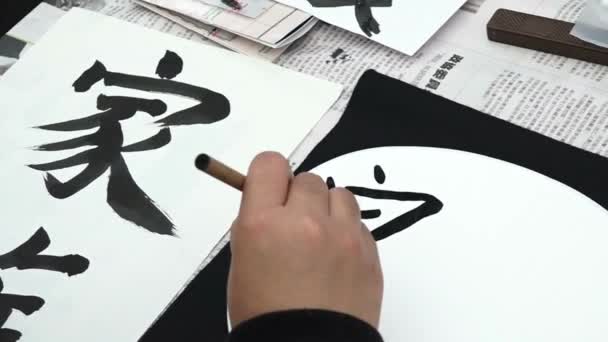アジア人が現地語を書いています 墨筆で書道を学ぶ チャイニーズ ジャパン — ストック動画