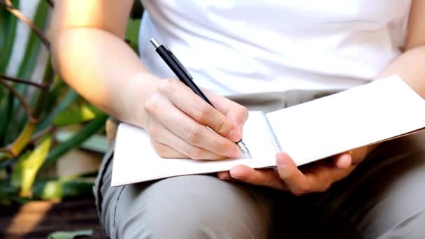 女人用钢笔写日记本的特写手 计划列出室外公园的日记 放松概念 — 图库视频影像
