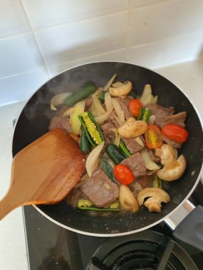 Tumis Daging Sapi Mercon ya da Kızartma ya da sotelenmiş soğanlı biftek, kırmızı arnavut biberi ve diğer bitki ve baharatlar. Beyaz tabakta servis ediliyor. Endonezya yemeği, yemek tarifi ve mutfağı