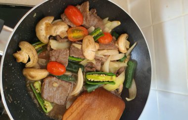 Tumis Daging Sapi Mercon ya da Kızartma ya da sotelenmiş soğanlı biftek, kırmızı arnavut biberi ve diğer bitki ve baharatlar. Beyaz tabakta servis ediliyor. Endonezya yemeği, yemek tarifi ve mutfağı