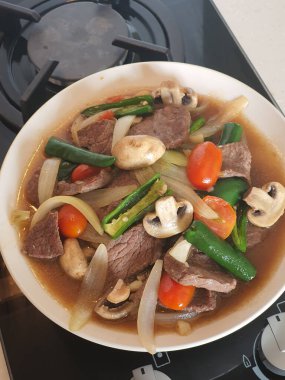 Tumis Daging Sapi Mercon ya da Kızartma ya da sotelenmiş soğanlı biftek, kırmızı arnavut biberi ve diğer bitki ve baharatlar. Beyaz tabakta servis ediliyor. Endonezya yemeği, yemek tarifi ve mutfağı