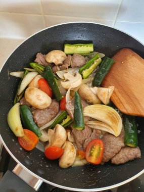 Tumis Daging Sapi Mercon ya da Kızartma ya da sotelenmiş soğanlı biftek, kırmızı arnavut biberi ve diğer bitki ve baharatlar. Beyaz tabakta servis ediliyor. Endonezya yemeği, yemek tarifi ve mutfağı