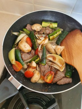 Tumis Daging Sapi Mercon ya da Kızartma ya da sotelenmiş soğanlı biftek, kırmızı arnavut biberi ve diğer bitki ve baharatlar. Beyaz tabakta servis ediliyor. Endonezya yemeği, yemek tarifi ve mutfağı