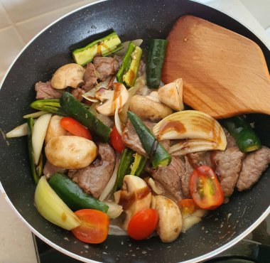 Tumis Daging Sapi Mercon ya da Kızartma ya da sotelenmiş soğanlı biftek, kırmızı arnavut biberi ve diğer bitki ve baharatlar. Beyaz tabakta servis ediliyor. Endonezya yemeği, yemek tarifi ve mutfağı