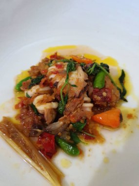 Tumis Cumi Cabe ya da kızarmış taze kalamar, yeşil biberli ve kırmızı Tayland biberli, beyaz kasede servis ediliyor. Endonezya geleneksel yemeği. Seçici odak.