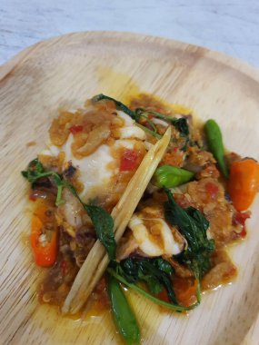 Tumis Cumi Cabe ya da kızarmış taze kalamar, yeşil biberli ve kırmızı Tayland biberli, beyaz kasede servis ediliyor. Endonezya geleneksel yemeği. Seçici odak.