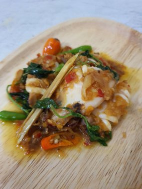 Tumis Cumi Cabe ya da kızarmış taze kalamar, yeşil biberli ve kırmızı Tayland biberli, beyaz kasede servis ediliyor. Endonezya geleneksel yemeği. Seçici odak.