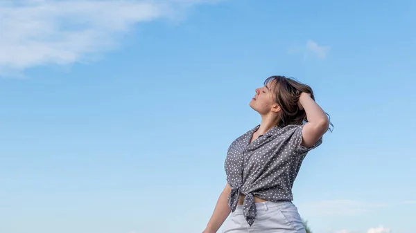 stock image young woman in a white shirt and a blue dress on a background of clouds