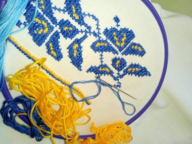 İşlemeli kumaş, mavi-sarı çiçekli, tuvale yakın plan.