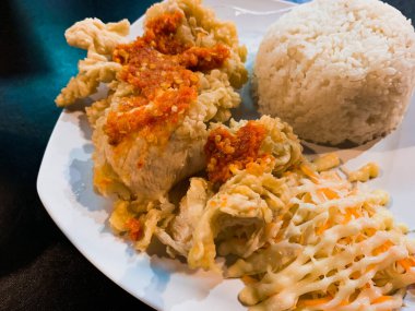 Ateşli Tavuk Geprek Cazibesi: Beyaz Tabakta Baharatlı Tavuk Geprek, Pirinç ve Sebzelerin Yakın Çekimi