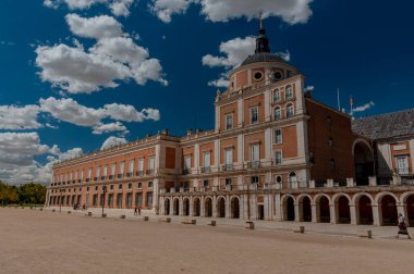 İspanya. Aranjuez. Kraliyet Sarayı 'nın çarşısı. Pencereli çatısı var. Yeşil çimenler. Royal Palace 'ın yanına park et. Taho Nehri. Sarayın yakınındaki kanal. Kanalın üzerindeki köprü. Mavi gökyüzü, beyaz bulutlar.