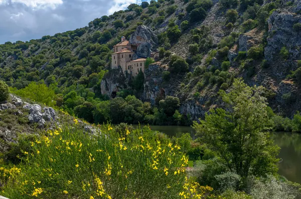 Bahar. Kırmızı gelincikler. Bahar çiçekleri. Kayadaki manastır. Yeşil çimenler. Çalılar. Taşlar. Sarı çiçekler. Mavi gökyüzü. Beyaz bulutlar. Nehir.