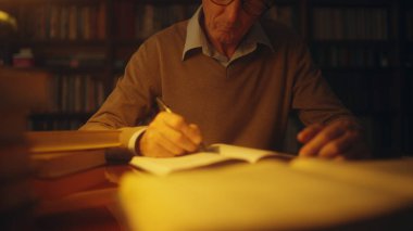 Kütüphanede çalışan kıdemli bilim adamı, akşamları notlar yazıyor, serbest çalışıyor.