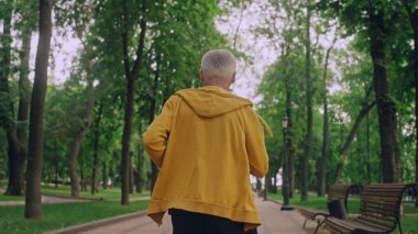 Athletic senior man running in park, healthy lifestyle in senior age, workout