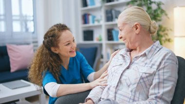 A smiling female social worker visits a senior lady at her home to provide support and care clipart