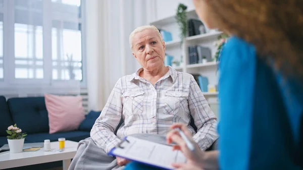 Μια Γυναίκα Γιατρός Ακούει Προσεκτικά Παράπονα Της Ηλικιωμένης Γυναίκας Και — Φωτογραφία Αρχείου