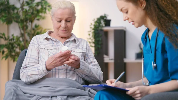 General practitioner prescribing pills to senior woman, personal home care