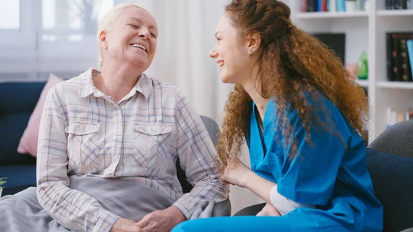 Dost canlısı hemşire ve kıdemli kadın içtenlikle gülüyor, konuşuyor ve eğleniyorlar.