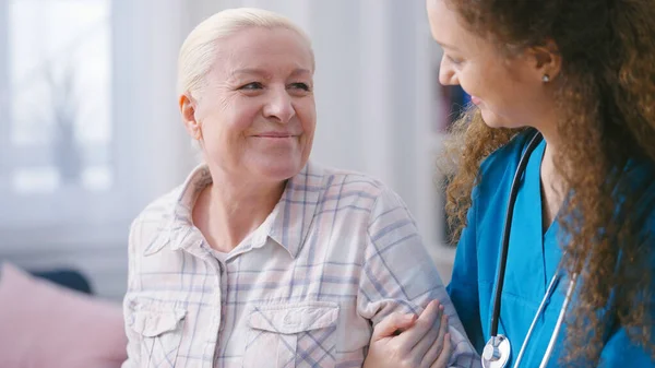 stock image Home nurse helping senior woman to stand up and take a walk, elderly care