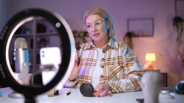 Bir kadın güzellik kanalı için makyaj dersi kaydediyor. Kozmetik bölümündeki işini vurguluyor.