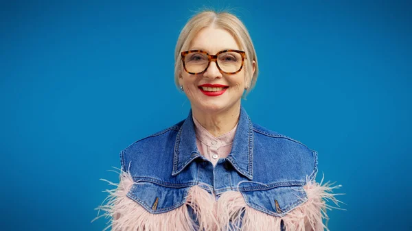 A stylish woman in her 50s, wearing a trendy jacket, is smiling at the camera, showcasing her fashion sense