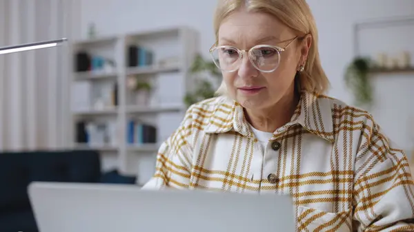 Mujer Concentrada Anteojos Escribiendo Ordenador Portátil Sentado Una Acogedora Oficina —  Fotos de Stock
