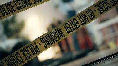 Evdeki suç mahalli uyarı bandıyla işaretlenmiş, polis delil topluyor.