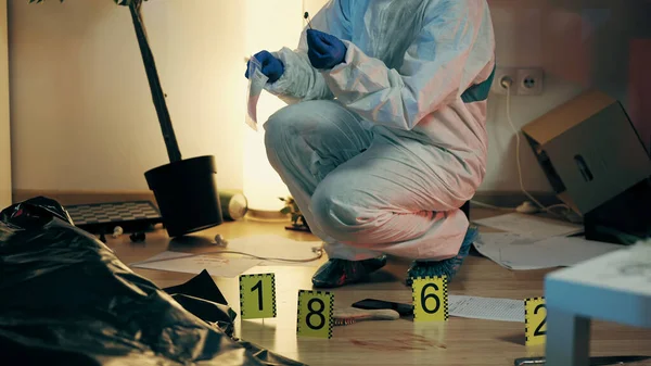 Bir adli tıp uzmanı kanıt torbasında mermi kovanı topluyor ve cinayet mahallini inceliyor.