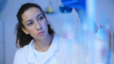 Kadın kozmetik uzmanı laboratuvar ve güzellik endüstrisinde sıvı örneklerini inceliyor.