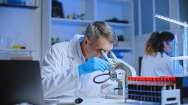 Laboratuvar çalışanı mikroskop altında incelemek için kan örneği alıyor. Sağlık kontrolü.