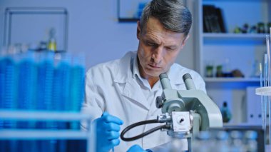 Sağlık laboratuarı çalışanı örnekleri mikroskop altında inceliyor, tanı koyuyor.