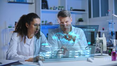 Laboratuvar bilim adamlarından oluşan bir ekip holografik ekranda hücre mutasyonunu inceliyor.