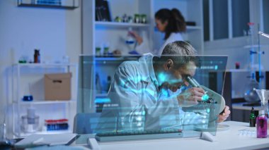 Kimyasal laboratuvar bilim adamı sıvıyı mikroskop altında inceliyor, deney yapıyor.