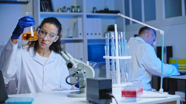 Cosmetic lab assistant mixing liquid substances, observing reaction, experiment